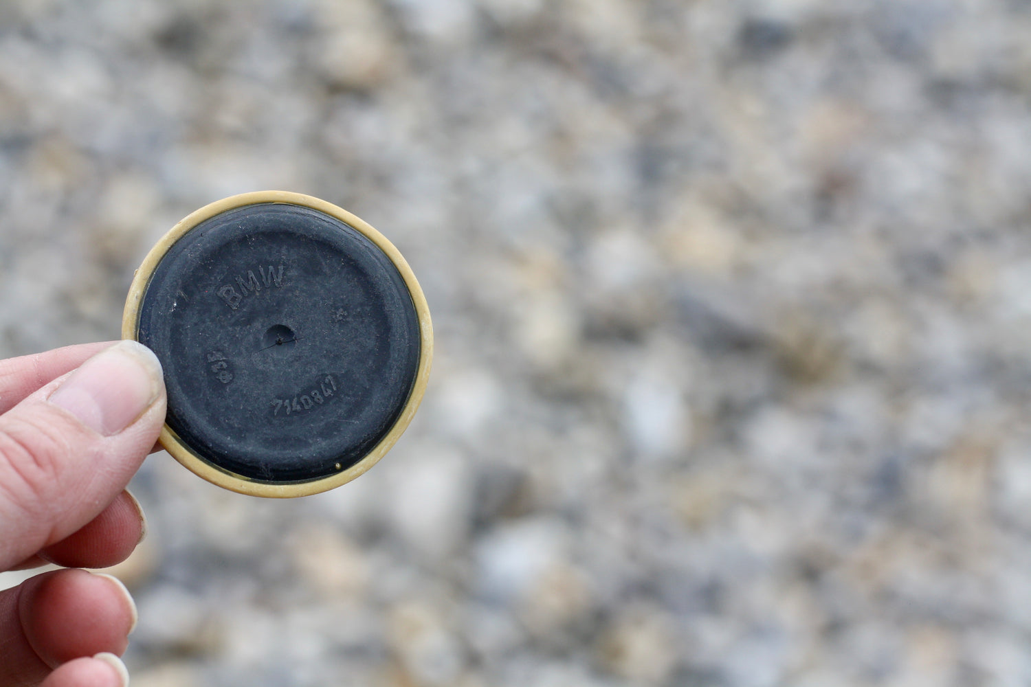 A white thumb and forefinger hold a BMW car part, washed up on a beach along ,the Jurassic Coast, following a container spill in 2007.