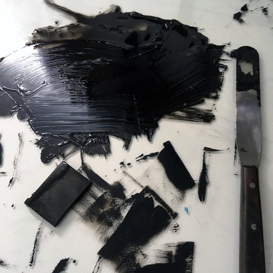 Black ink and palette knife on glass topped work surface.