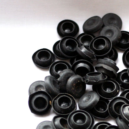 A pile of discarded rubber blanking plugs, sit on a white background.