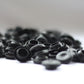 A collection of black rubber blanking plugs, sit against a white surface.
