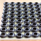 A series of 81 upturned rubber blanking plugs, form a grid. They are glued to a piece of reclaimed wooden board. The board sits on a wooden table.