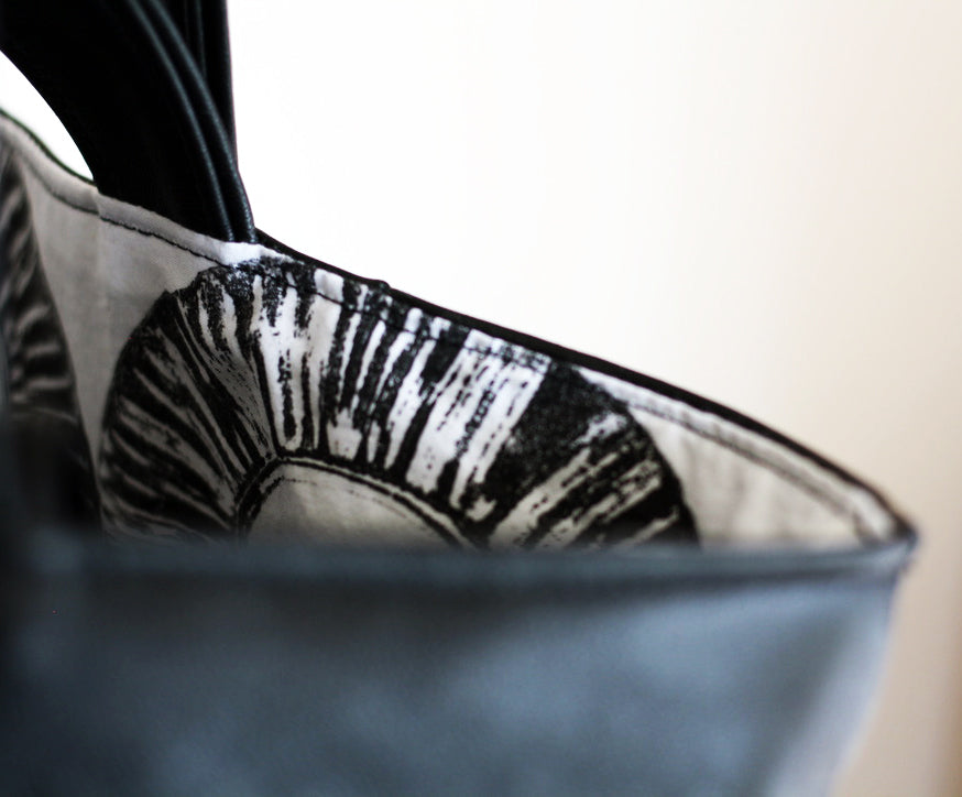A close up detail of a hand printed tote bag lining, with textured black rings on white cotton.