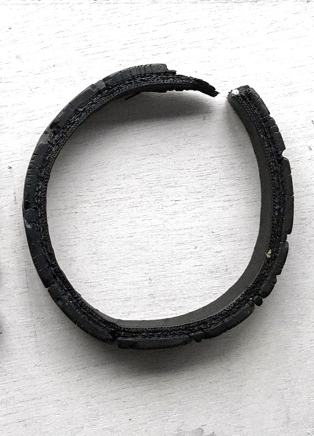 A piece of black rubber tyre on a white wooden surface.